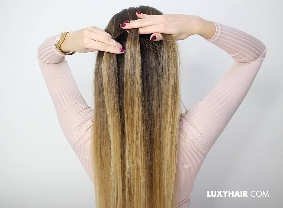 A woman with long blonde hair is applying Dutch braid hair extensions, showcasing her creativity and style.