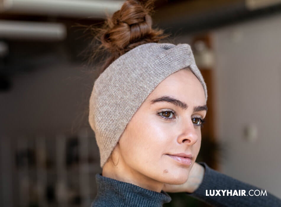 A woman with a knotted hair tie headband, wearing hair extensions.