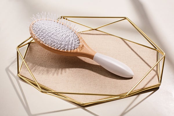 A golden tray holding a wooden brush.