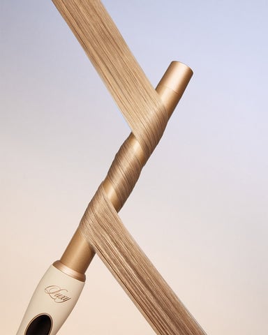 A close up of a hair curling wand with hair extensions wrapped around it.