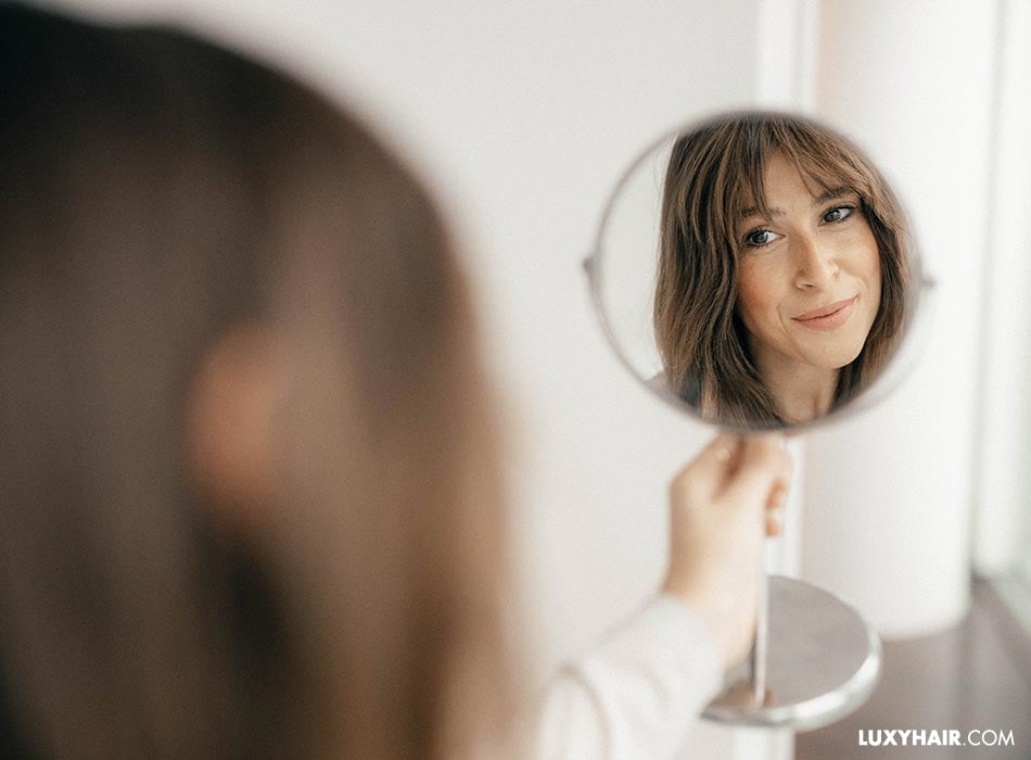 A smiling woman looking at herself in the mirror.