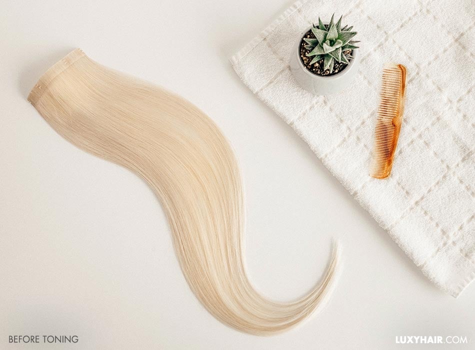 Hair extensions and a comb placed on a white towel.