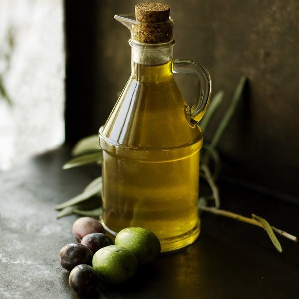 Glass bottle of olive oil with fresh olives